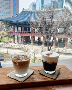 two cups of coffee sit on a wooden table