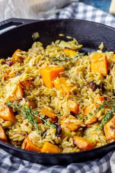 a skillet filled with rice and vegetables on top of a checkered table cloth