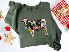 DESCRIPTION   Christmas Lights Cow Shirt, Santa Hat Moo, Farm Party Tee, Family Trip Shirt, Holiday Gift Shirt, Merry Festive Sweatshirt CONSTRUCTION DTG printing with eco-friendly and child-safe inks. All shirts are pre-shrunk with a tear-away label. Twill tape Shoulder-to-shoulder to stabilize and prevent stretching. Side-seamed for better structural support. Ribbed knit collar for less stretching. SIZING Please reference our posted sizing chart for more specific garment dimensions and feel fr Cow Tops, Christmas Cow, Cow Shirt, Western Christmas, Round Neck Sweatshirts, Sweatshirt Christmas, Cute Cows, Holiday Sweater, Unique Christmas Gifts