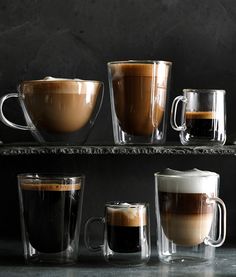 three different types of coffee cups on a shelf with one being filled with liquid and the other is empty