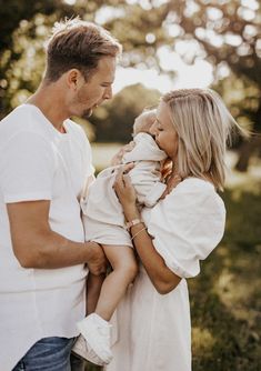 a man and woman holding a baby in their arms