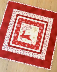 a red and white quilted placemat with a reindeer on it's side