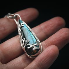 Several hand sawn coral-inspired branches fold across this stunning, teal teardrop shaped Labradorite stone. Ensconced in a custom hand built setting made out of .925 Sterling Silver, and featuring a decorative wrapped bezel to offset the gem. Polished to a high shine. Handmade Labradorite Teardrop Jewelry, Artisan Hand Wrapped Teardrop Pendant Jewelry, Hand Forged Teardrop Nature-inspired Jewelry, Handmade Teardrop Jewelry, Nature-inspired, Handmade Teardrop Nature-inspired Jewelry, Handmade Nature-inspired Teardrop Jewelry, Unique Labradorite Teardrop Pendant Jewelry, Nature-inspired Teardrop Wire Wrapped Jewelry, Nature-inspired Teardrop Gemstone Jewelry