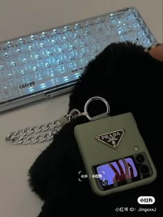 a keychain with a camera attached to it and a computer keyboard in the background