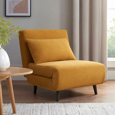 a yellow chair sitting next to a table with a white vase on top of it