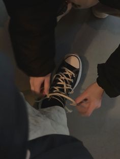 two people tying up their shoes with laces on the bottom and one person standing in front of them