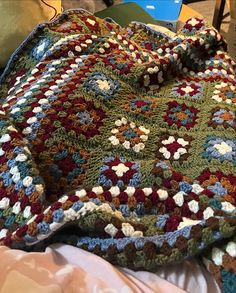 a crocheted granny blanket is laying on a bed next to a laptop computer