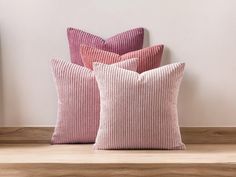 three pink pillows sitting on top of a wooden table