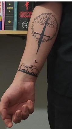 a person with a tattoo on their arm holding the hand of another person in front of a bookshelf