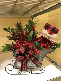 a sleigh filled with red and black flowers, greenery and a hat