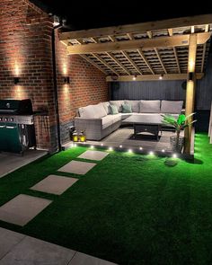 an outdoor living area is lit up with lights and green grass on the ground,