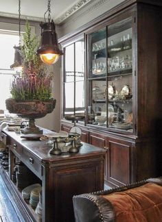 an old fashioned dining room with lots of glassware and plants in the centerpiece