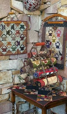 a table with quilts on it next to a stone wall