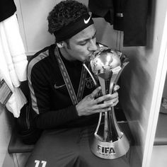 a man sitting in a locker room kissing the soccer ball on top of a trophy