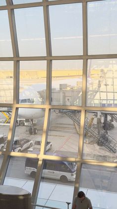 an airport terminal looking out the window at planes on the tarmac and parked cars