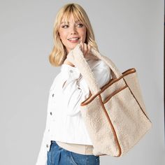 Add a touch of elegance to your daily look with the Toasty Tote. Crafted from luxurious cream-hued faux shearling, the bag features an eye-catching contrast with its faux suede binding and bottom panel. Secure your belongings with a zip pocket and snap button closure details. Carry your essentials in style with this must-have luxury piece. Features: Color: CreamMaterials: 100% PolyesterSize: 19" wide, 13" tall, 7" deepHandle: 10" Drop Cream Shoulder Bag For Winter Travel, Winter Travel Cream Shoulder Bag, Winter Cream Shoulder Bag For Daily Use, Cream Tote Shoulder Bag For Winter, Winter Cream Tote Shoulder Bag, Casual Shoulder Bag With Plush Lining For Everyday, Winter Shoulder Bag With Zipper For On-the-go, Winter Shoulder Bag With Zipper Closure For On-the-go, Chic Everyday Shoulder Bag With Plush Lining