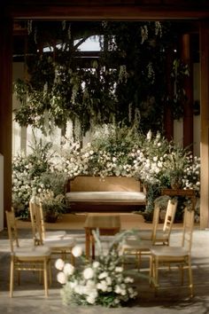 an arrangement of flowers and greenery is arranged around a wooden table in front of a bench