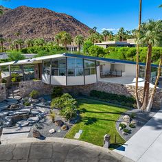 an aerial view of a house with palm trees and mountains in the backround