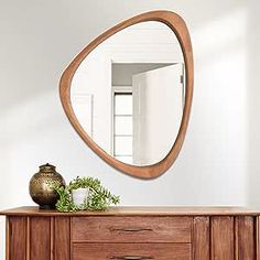 a wooden dresser with a mirror above it and a vase on the sideboard next to it