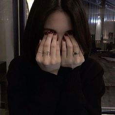 a woman covering her face with both hands while sitting in front of a glass door