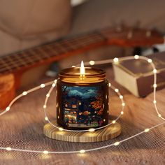 a lit candle sitting on top of a wooden table next to a string of lights