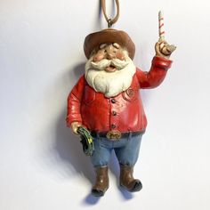 an ornament with a man holding a candy cane in one hand and a candle in the other