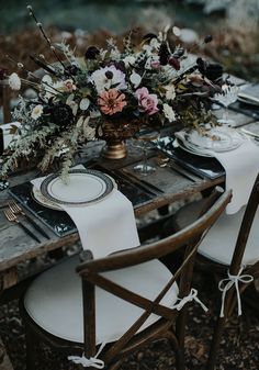 a wooden table topped with white plates and flowers