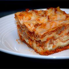 a white plate topped with lasagna covered in cheese