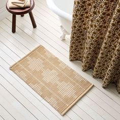 a bath tub sitting next to a rug on top of a wooden floor in a bathroom