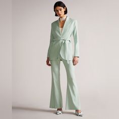 a woman wearing a green suit and white shoes