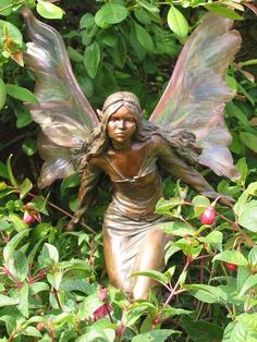 a statue of a fairy sitting in the bushes