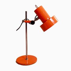 an orange table lamp with two lamps on it's sides and one light turned on