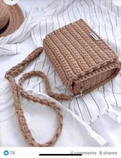 a brown purse sitting on top of a bed next to a white shirt and hat