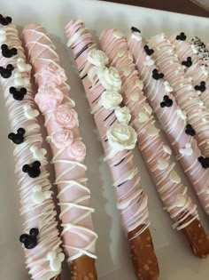 some very pretty decorated desserts on a white plate with black and pink icing