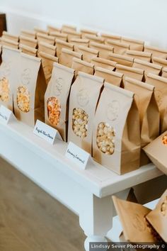 there are many bags that have popcorn in them on the table with name tags attached to them