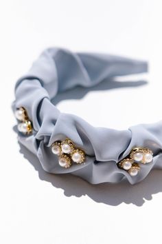 Content Light blue chiffon, ruched headband. Pearl embellishing along top. Care Spot clean if needed. Avoid exposure to water, lotion, and/or fragrance. This headband has light blue ruched fabric that fully encompasses the headband base. The cute gold and pearl embellishments on top are the perfect add to any outfit! old money aesthetic, classic style, birthday gift, gift ideas, hair inspiration, hairstyles, feminine hairstyle, headband, fabric headband, hair accessories, embellished headband Feminine Hairstyles, Ivy City Co, City Light, Embellished Headbands, Fabric Headbands, White Dress Party, Bridesmaids And Groomsmen, Pearl Headband, Girls Dresses Summer