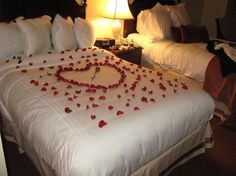 a bed with rose petals in the shape of a heart