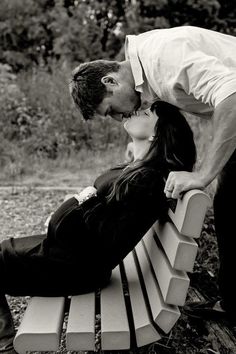 a man and woman kissing on a bench