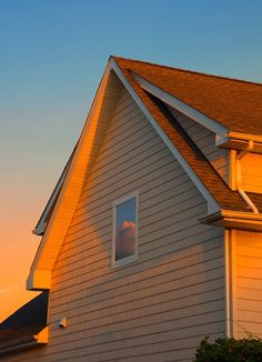 the sun is setting behind a house with a clock on it's front porch