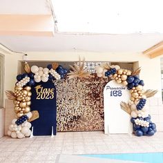 an entrance decorated with balloons and decorations for a graduation party or other function in blue, gold and white colors