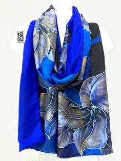 This is a hand painted silk shawl wrap with the design of Japanese art. This magnificent light weight blue silk shawl is crafted with two pure silk panels to keep your body wrapped up in warmth with style. The exquisite Japanese Art of Kimono Lily design is hand drawn in gold and black accented with pearl white stamens in the center of the flowers. This beautiful Kiono Lily Shawl makes one of a kind unique gift silk painting art will make an unforgettable Japanese Gift for a lady who loves art. Gold Kimono, Wing Scarf, Lily Design, Blue Silk Scarf, Hand Painted Scarves, Painted Scarf, Bridal Shawl, Silk Scarf Painting, Hand Painted Silk Scarf