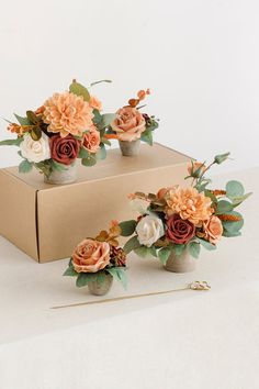 three vases filled with flowers sitting on top of a table next to a box