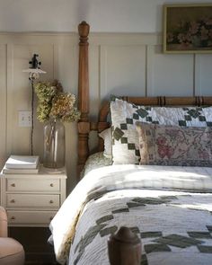 a bed sitting next to a white dresser with flowers on it's headboard