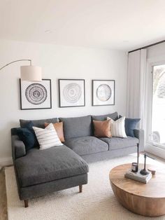 a living room with gray couches and pictures on the wall above it's coffee table