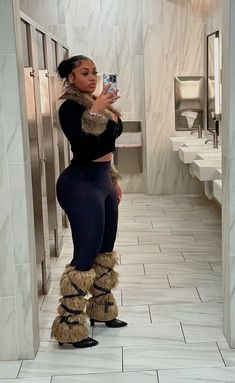 a woman taking a selfie in a public restroom wearing furry boots and leg warmers