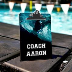 a sign that says coach aaron next to a swimming pool with water in the background