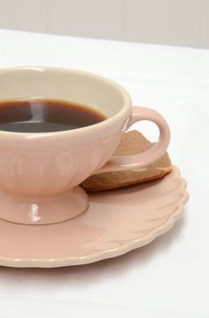 a cup of coffee on a saucer with a piece of bread next to it