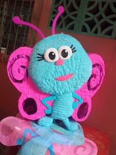 a blue and pink stuffed animal sitting on top of a table next to another toy