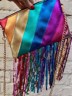 a woman holding a rainbow colored purse with chains hanging from it's sides and the bottom