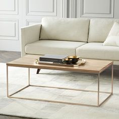 a living room with a couch, coffee table and rug on the floor in front of it